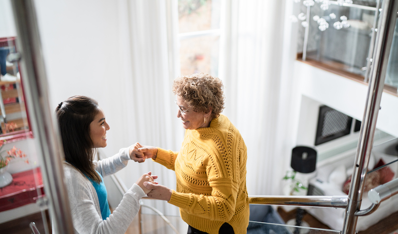 Home health care worker helping older woman.