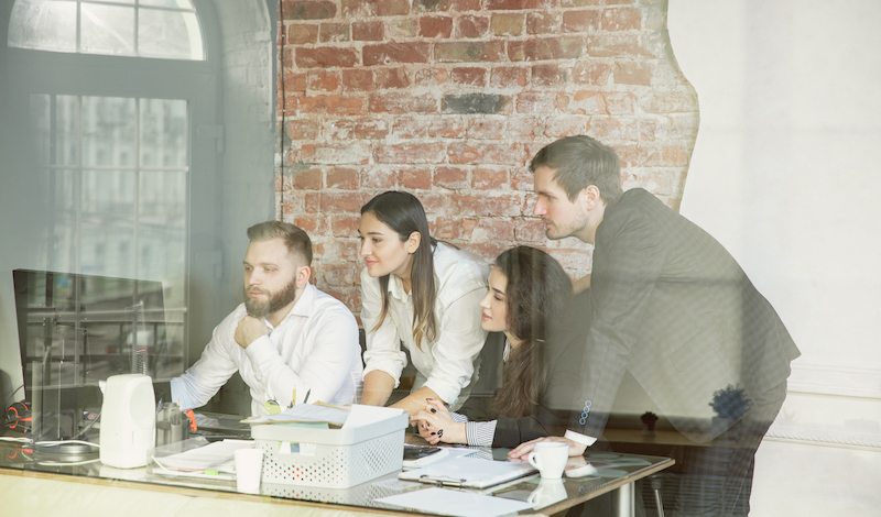 Group working, surrounding a computer.